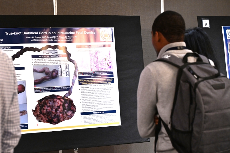 Carlton Mamo takes in a poster at the Advances in Forensic Pathology poster session and reception.